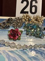 All jewellery pieces laid out including rose pin, crystal beads, Weiss brooches and earrings, pearl earrings