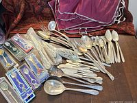 Overall lot showing packaged Disney spoons, loose silver-plated flatware, storage cloth
