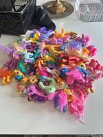 Pile of assorted My Little Pony figures and parts on table