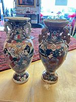Front view of both vases showing hand-painted motifs and general condition