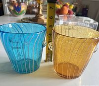Blue and amber ice buckets side by side with tape measure showing height