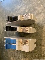 Three slim tandem breakers with black and blue handles showing side labels