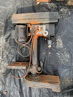 Full view of rusty benchtop drill press showing base, column, motor and chuck