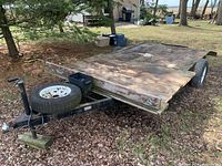 Side view of flatbed trailer showing wood deck, single axle and tongue