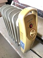 overall view of compact oil-filled radiator heater showing carry handle, control panel and fins