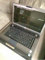 Laptop open on couch showing screen, keyboard and chassis