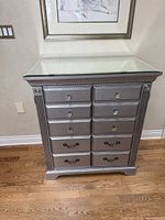 Front view of silver entertainment chest with mirrored top and faux drawer fronts