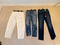 All three pairs of jeans laid flat on hangers showing front view