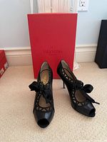 Pair of Valentino Garavani black leather lace-up heels in front of original red box