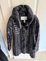 Front view of black quilted puffer jacket on hanger
