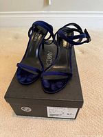 Front view of blue velvet sandals on box