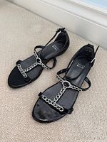 Top view of both sandals showing chain T-strap and branding on insoles