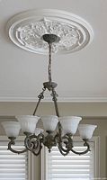 Chandelier close-up showing metal frame, frosted glass shades and chain