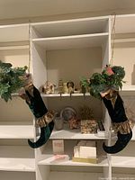 Full shelf showing all holiday items including hanging elf boots, brass angels, glass votives, cards