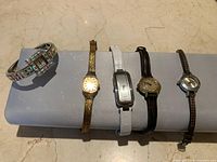 Five assorted women's wristwatches displayed on roll