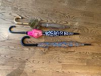 Three closed umbrellas on wood floor showing handles and canopy patterns