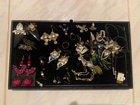 Black tray displaying assorted costume jewellery items