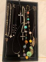 Tray containing assorted necklaces with various pendants and beads