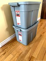 Two stacked grey Rubbermaid storage totes showing labels and side handles