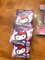 Three purple boxed Yu-Gi-Oh x Hello Kitty plush keychains stacked
