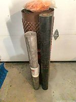 Three rolled construction materials standing upright