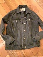 Garage black denim jacket laid flat front view showing button closure and pockets
