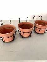three terracotta pots in black metal hanging frames