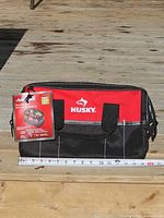 Front view showing Husky logo, tag, exterior pockets, measuring tape indicating 15" length