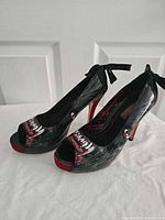 Side view of both pumps showing graphic print, bows, heel height