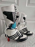 Side view of both boots showing color scheme, lace-up, Velcro strap, red heel