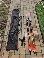Full lot: skis with bindings, poles, and ski bag laid out