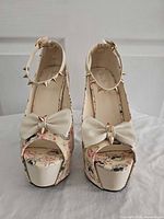 Front view of both platform heels showing bows, ankle straps, spike studs