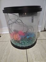 Front view showing entire cylindrical aquarium, filter, gravel and decorations