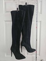 Full view of both thigh-high boots hanging, measuring tape visible indicating 29 in length