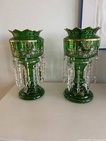 Front view of both emerald green glass mantle lustres with crystal prisms displayed
