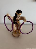 Full view of hoop dancer corn husk doll holding two hoops