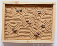 Top view of cedar tray filled with sand and stones arranged in patterns