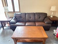 Front view of brown leather sofa with coffee table and end tables