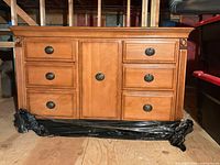 Front view of light brown dresser showing six drawers and center door