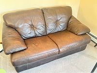 Front view of brown leather tufted loveseat
