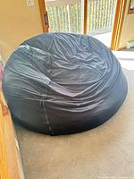 Full view of oversized black bean bag chair on floor