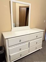 Front view of white six-drawer dresser with attached mirror