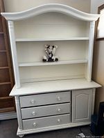Front view of white painted wood hutch with shelves, drawers and cabinet door