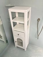 Full view of white bathroom storage tower showing open shelves, drawer, and cabinet door