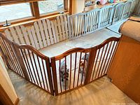 Overall view showing freestanding wood pet gate sections in use forming enclosure