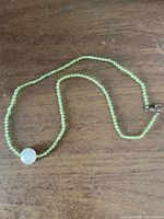 Full view of peridot bead necklace with coin pearl pendant