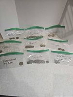 Overview of nine labelled bags of coins