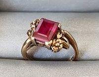Front view of gold ring showing square ruby and floral setting