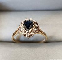 Ring angled view showing sapphire, diamond halo, and gold shank