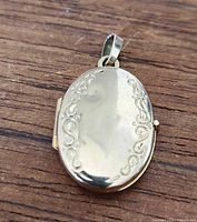 Front view of oval gold locket showing scroll border design